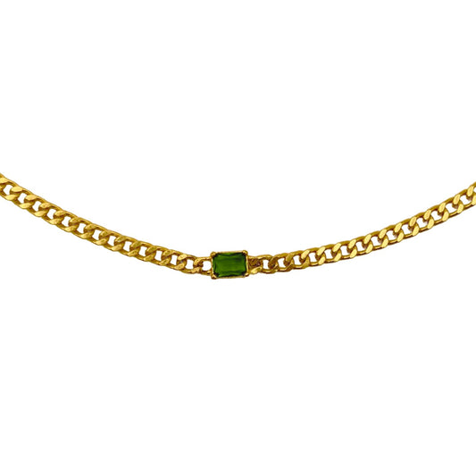 Gold chain with a green gemstone on a white background